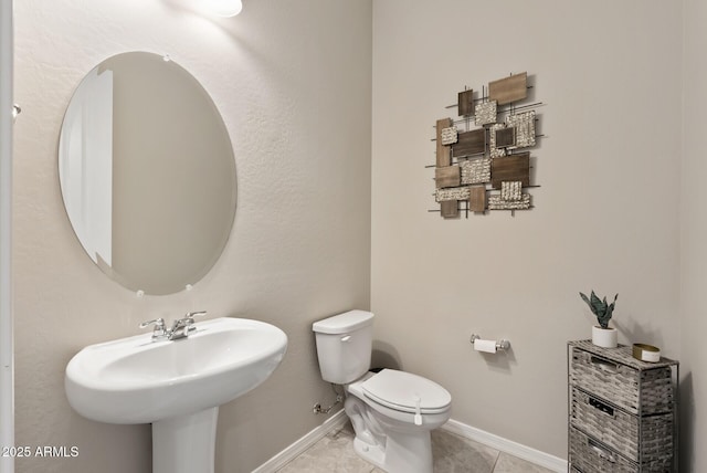 bathroom with a sink, baseboards, tile patterned floors, and toilet