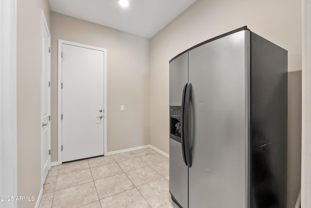 kitchen featuring stainless steel refrigerator with ice dispenser, baseboards, and light tile patterned flooring