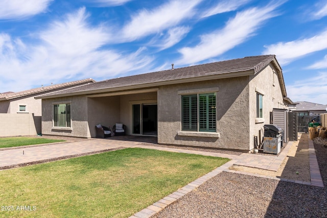 back of house with a lawn, fence, a patio area, and stucco siding