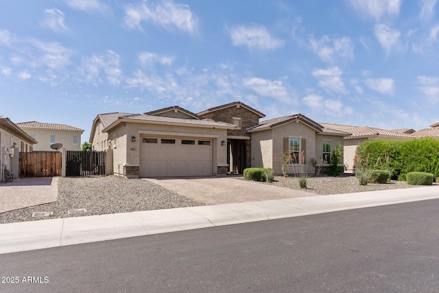 view of front facade with a garage, fence, decorative driveway, stucco siding, and a gate