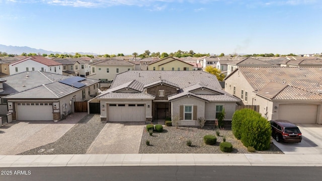 view of front of property with a tiled roof, an attached garage, driveway, and a residential view