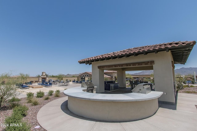 view of patio with a grill, a mountain view, and an outdoor kitchen