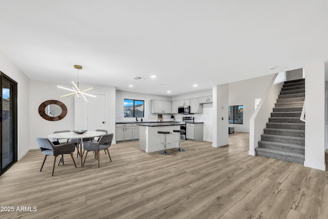 kitchen with a breakfast bar, a chandelier, a center island, light hardwood / wood-style floors, and stainless steel appliances