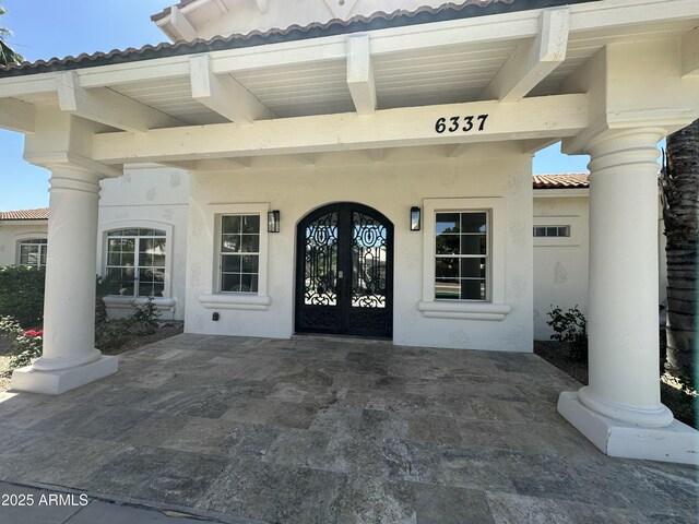 view of exterior entry featuring stucco siding and a tile roof