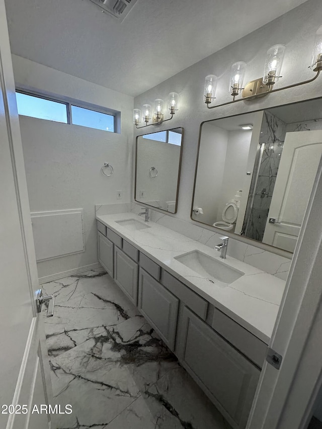 full bath with double vanity, visible vents, marble finish floor, and a sink