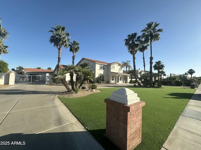 mediterranean / spanish home with a gate, a front lawn, and concrete driveway