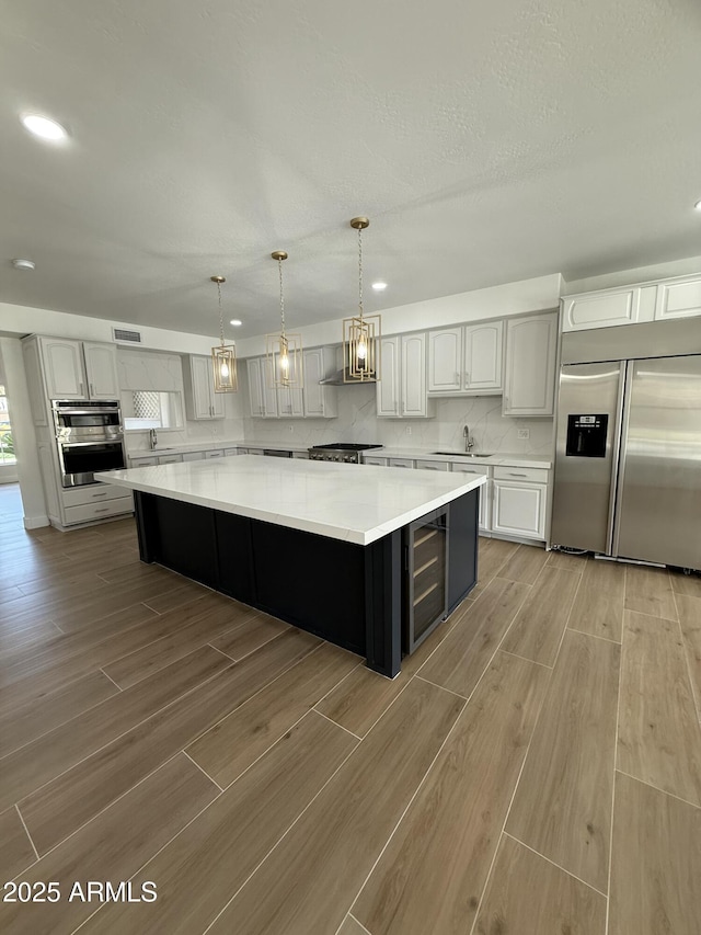 kitchen featuring built in fridge, a spacious island, light wood finished floors, light countertops, and wine cooler