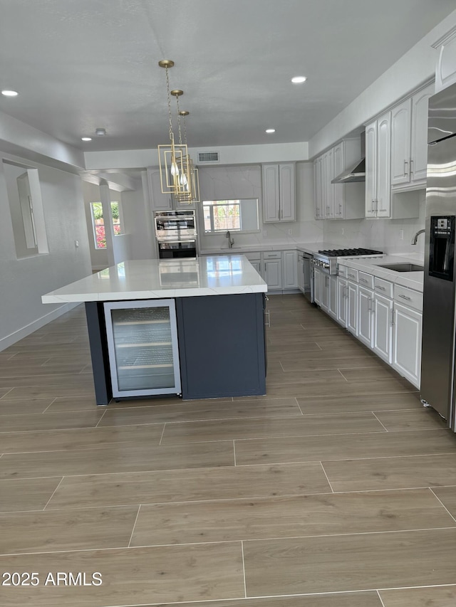 kitchen featuring beverage cooler, light wood-type flooring, stainless steel appliances, light countertops, and visible vents