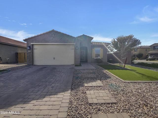 view of front facade with a garage, a tiled roof, decorative driveway, a front yard, and stucco siding