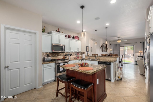 kitchen with pendant lighting, a breakfast bar, kitchen peninsula, stainless steel appliances, and ceiling fan