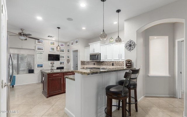 kitchen featuring tasteful backsplash, white cabinetry, a kitchen breakfast bar, decorative light fixtures, and ceiling fan