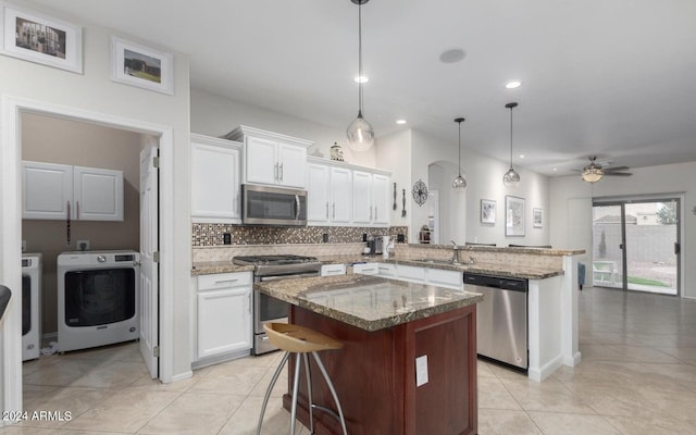 kitchen with washer / clothes dryer, white cabinetry, kitchen peninsula, appliances with stainless steel finishes, and decorative light fixtures