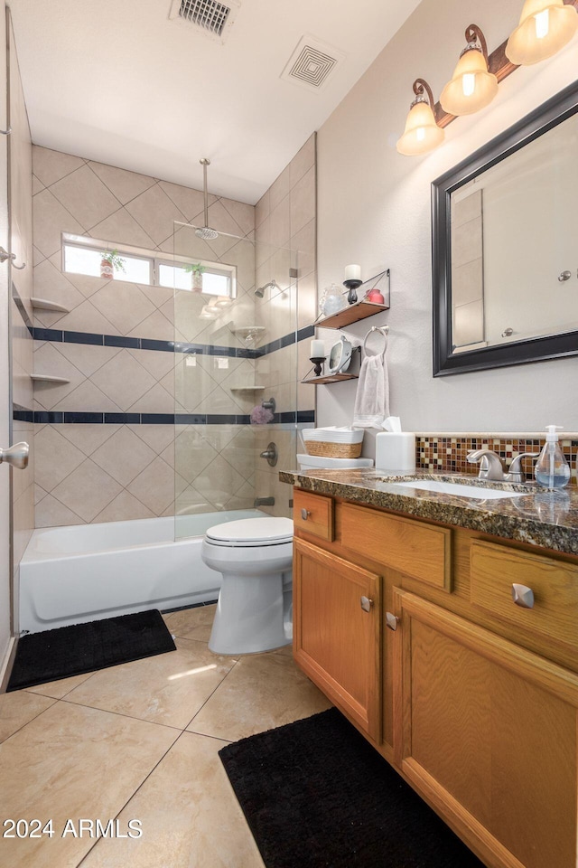 full bathroom featuring tasteful backsplash, vanity, tiled shower / bath combo, tile patterned flooring, and toilet