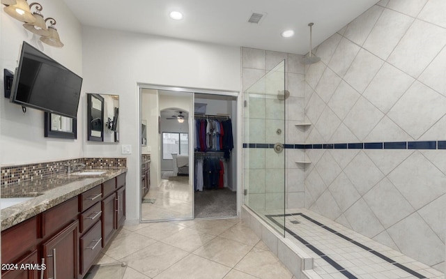 bathroom with ceiling fan, vanity, tile patterned flooring, and tiled shower