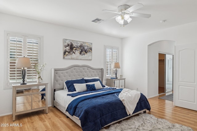 bedroom with visible vents, wood finished floors, arched walkways, baseboards, and ceiling fan