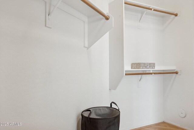 walk in closet with light wood finished floors