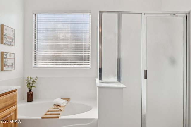 bathroom featuring a bath, a shower stall, and vanity