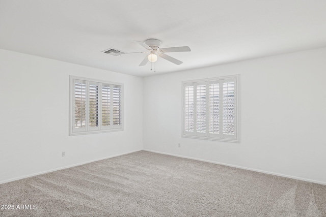 carpeted spare room featuring baseboards, visible vents, and ceiling fan