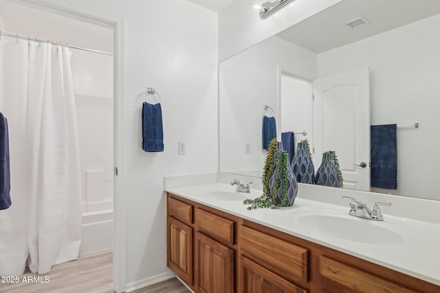 bathroom featuring a sink, visible vents, wood finished floors, and double vanity