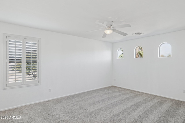 spare room with baseboards, carpet, visible vents, and ceiling fan