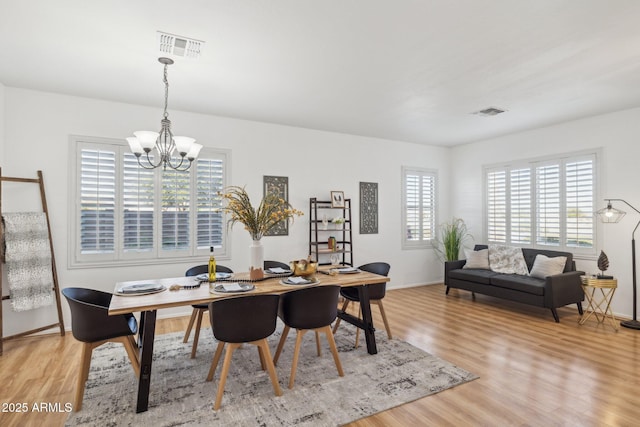 dining space with visible vents, baseboards, a chandelier, and light wood finished floors