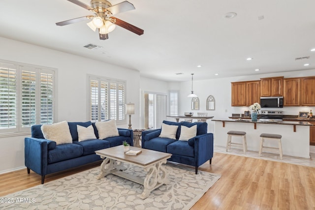 living area featuring visible vents, light wood-style flooring, and plenty of natural light