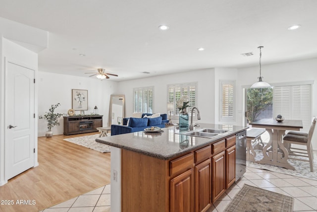 kitchen with light tile patterned floors, visible vents, a sink, stainless steel dishwasher, and brown cabinets