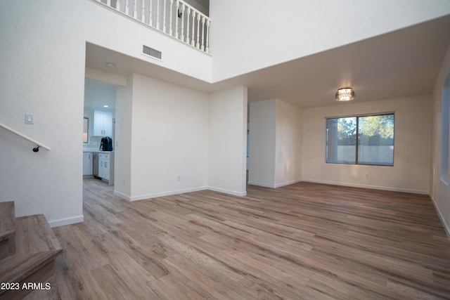 unfurnished living room with light hardwood / wood-style flooring and a towering ceiling