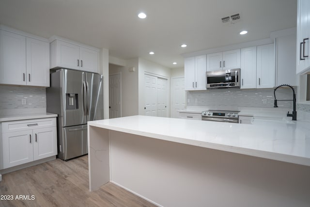 kitchen featuring decorative backsplash, white cabinetry, light hardwood / wood-style flooring, and stainless steel appliances