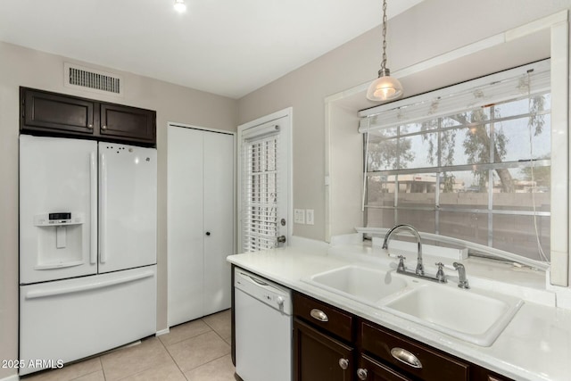 kitchen featuring pendant lighting, white appliances, sink, dark brown cabinets, and light tile patterned flooring