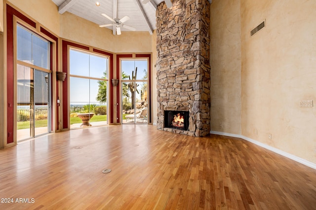 unfurnished living room featuring high vaulted ceiling, light hardwood / wood-style floors, beam ceiling, and a healthy amount of sunlight