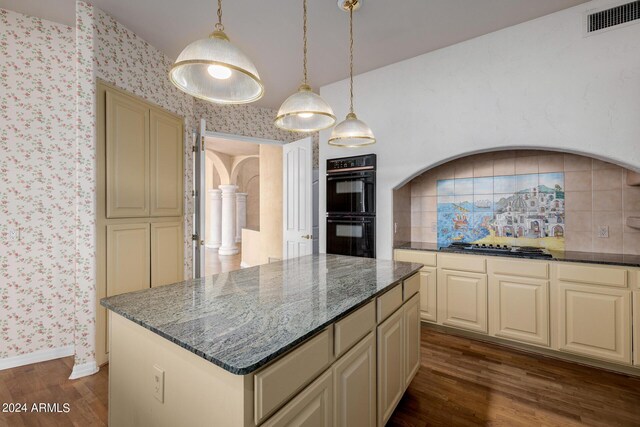 kitchen with a kitchen island, dark hardwood / wood-style flooring, hanging light fixtures, cream cabinetry, and double oven