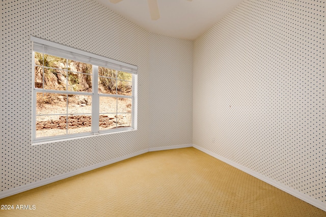 carpeted spare room featuring a wealth of natural light and ceiling fan