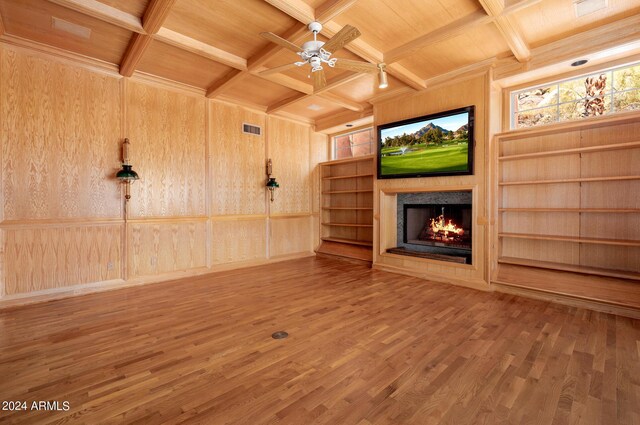 unfurnished living room featuring coffered ceiling, wood walls, wood-type flooring, ceiling fan, and beam ceiling