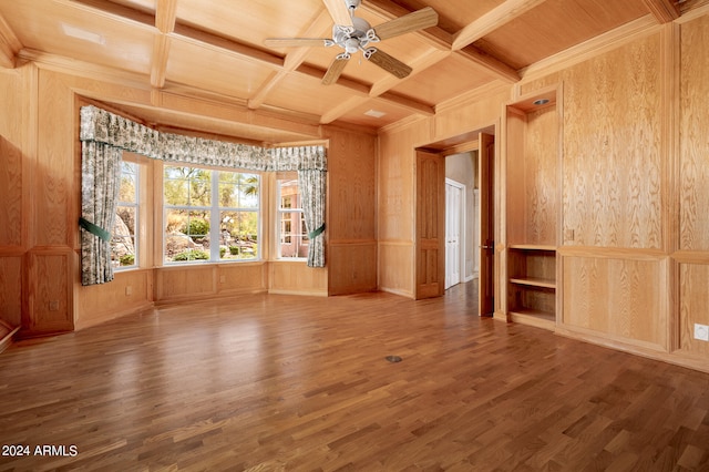 spare room featuring coffered ceiling, wood-type flooring, and wood walls