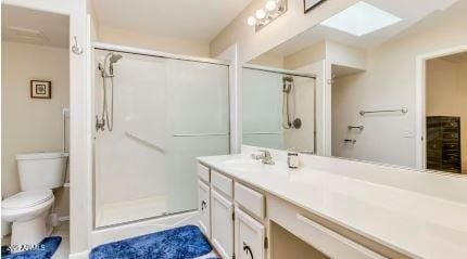 bathroom with vanity, a shower with door, and toilet