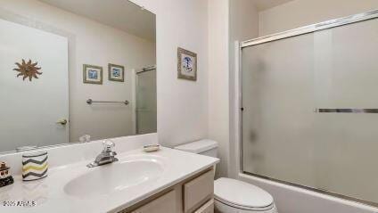 full bathroom with bath / shower combo with glass door, vanity, and toilet