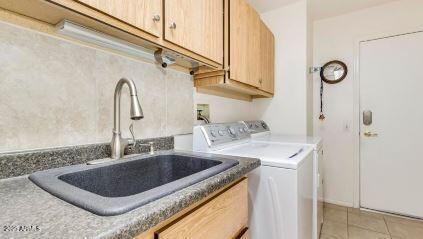 laundry room featuring sink, light tile patterned floors, cabinets, and independent washer and dryer