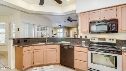 kitchen featuring sink, black appliances, a raised ceiling, light brown cabinetry, and kitchen peninsula