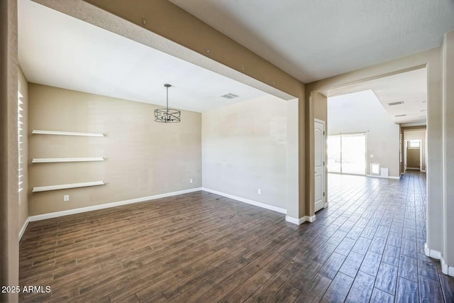 empty room with visible vents, dark wood finished floors, and baseboards