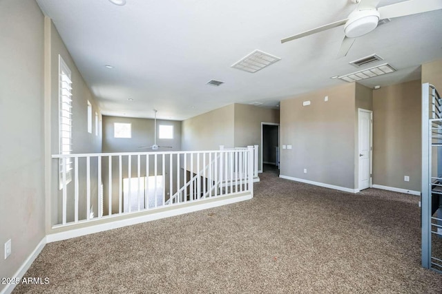 carpeted empty room featuring visible vents, ceiling fan, and baseboards