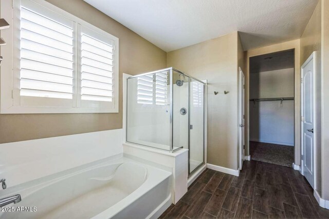 bathroom featuring a stall shower, a walk in closet, a garden tub, and wood finished floors