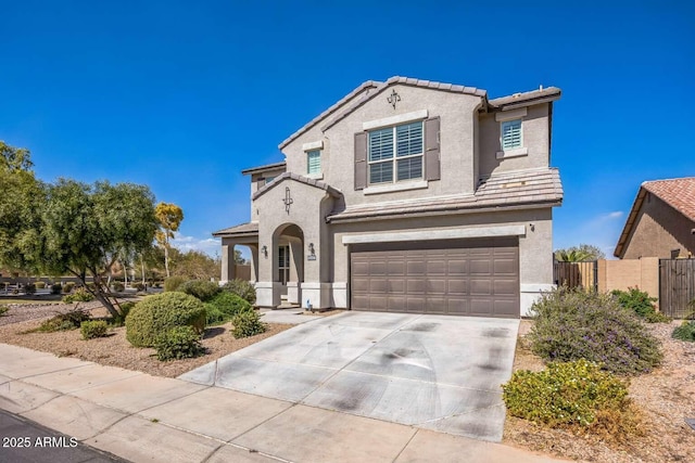 view of front facade with an attached garage, fence, a tile roof, driveway, and stucco siding