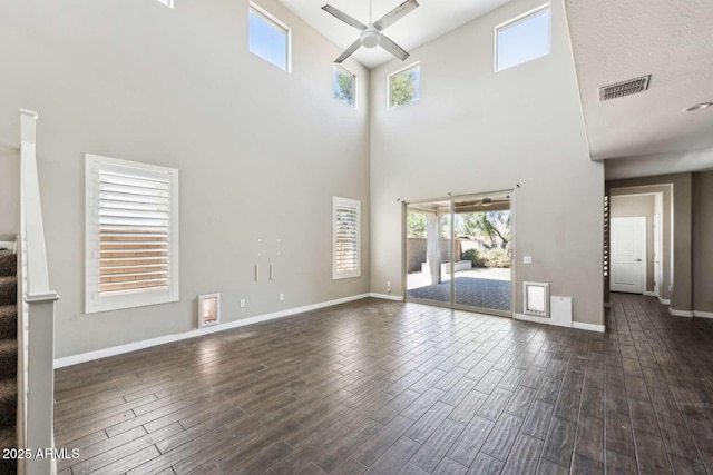 unfurnished living room featuring dark wood-type flooring, stairway, a ceiling fan, and baseboards