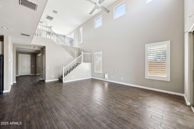 unfurnished living room with ceiling fan, stairway, dark wood-style flooring, and visible vents