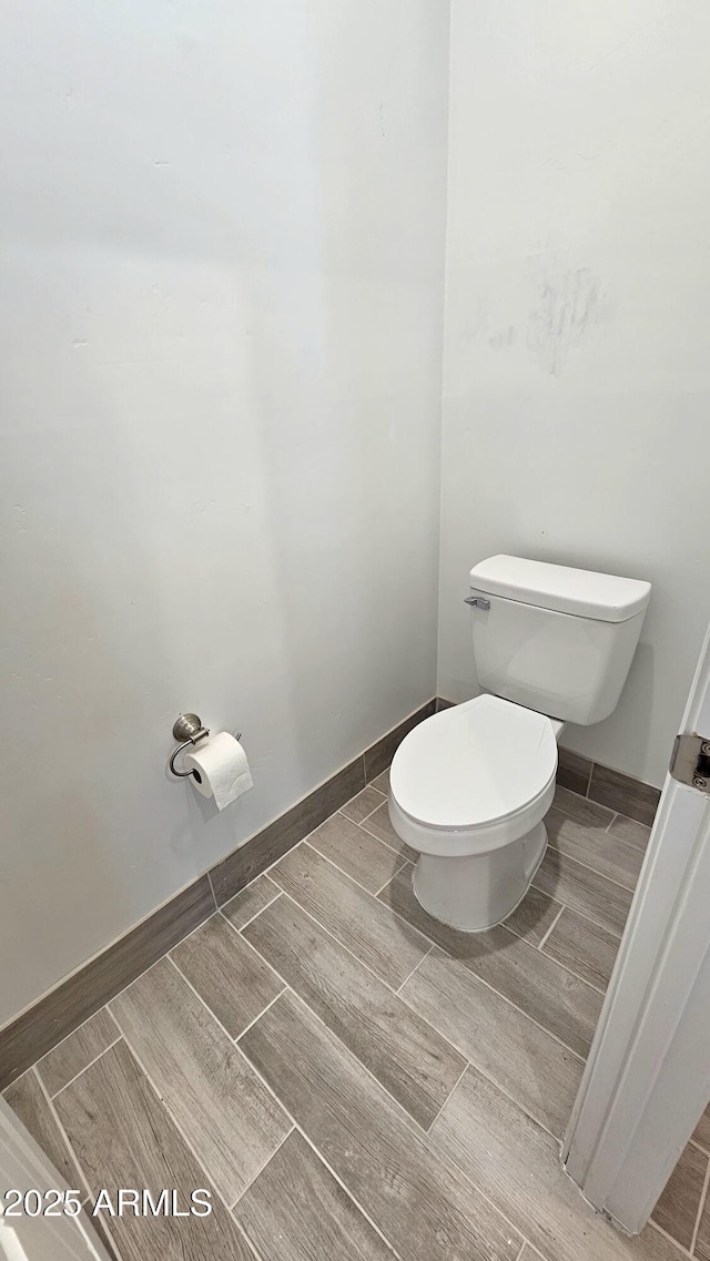 bathroom with toilet, baseboards, and wood tiled floor