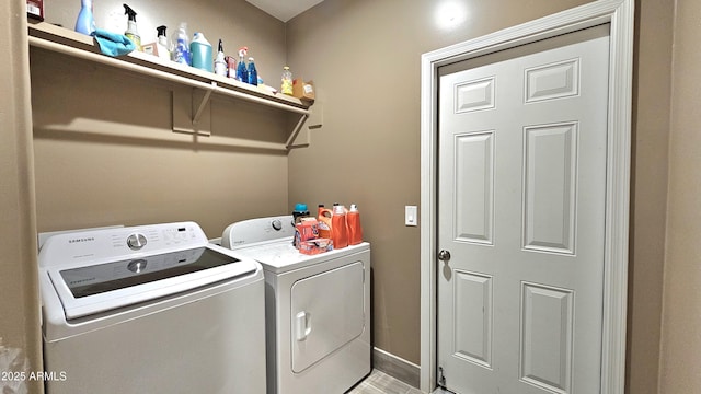 clothes washing area with laundry area, washer and dryer, and baseboards