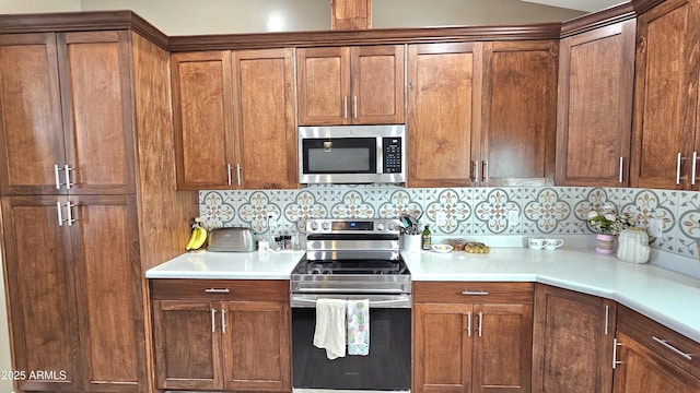 kitchen featuring light countertops, brown cabinetry, backsplash, and stainless steel appliances