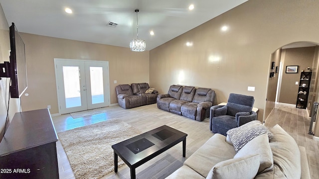 living room featuring light wood finished floors, visible vents, arched walkways, and french doors