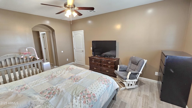 bedroom featuring a ceiling fan, visible vents, baseboards, arched walkways, and light wood-type flooring